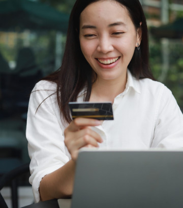 Asian woman shopping online with credit card and laptop computer in coffee shop cafe